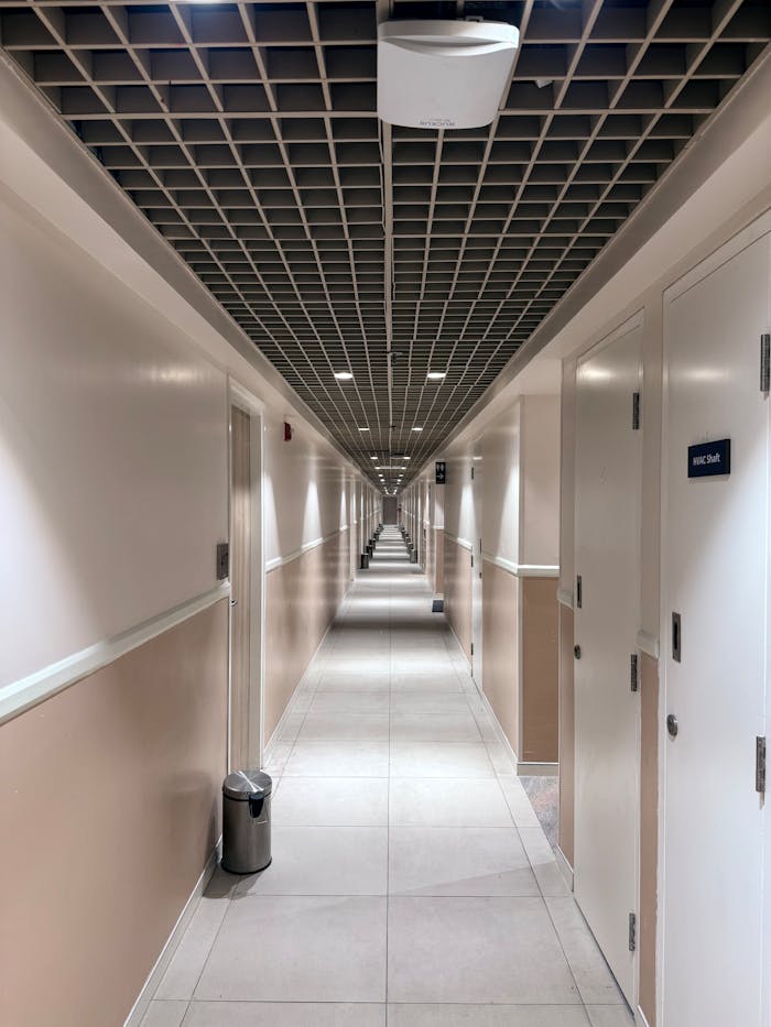A sleek, modern corridor with symmetrical design, white doors, and tiled flooring.
